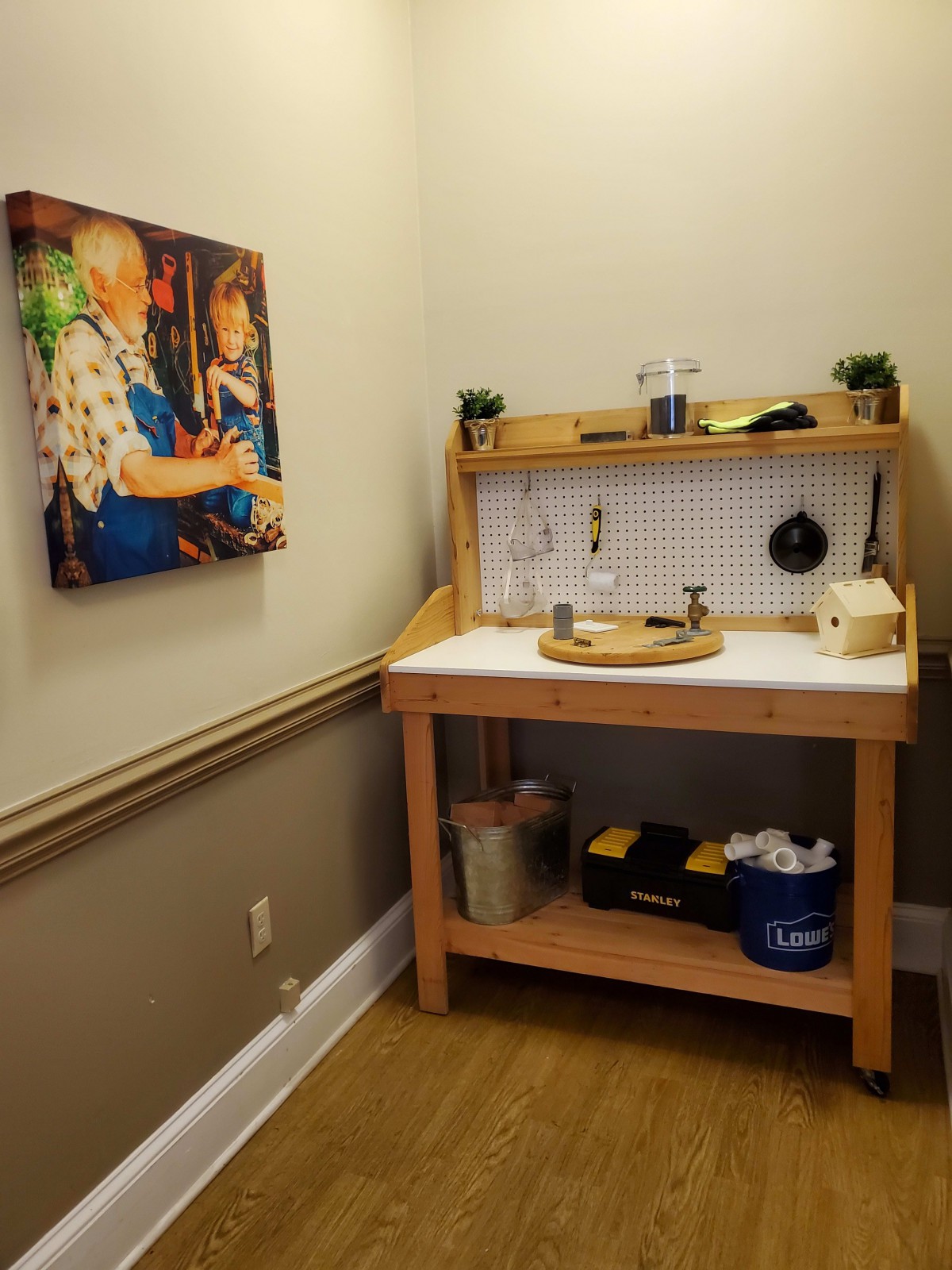 A cozy hobby corner featuring a wooden workbench equipped with tools and supplies, alongside a colorful painting on the wall.