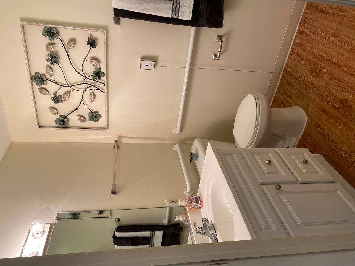 A clean and organized bathroom with a sink, toilet, mirror, and decorative wall art.