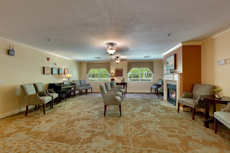 A spacious living room with elegant furniture and a fireplace, featuring large windows that let in natural light.