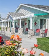 A quaint motel exterior with a row of units, adorned with star decorations and accompanied by a garden with blooming flowers.