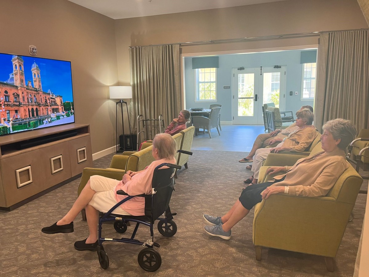A group of elderly people watching television in a comfortable room.
