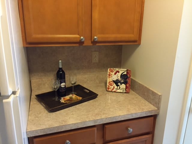 A kitchen corner with a countertop, cabinets, and wine decor.