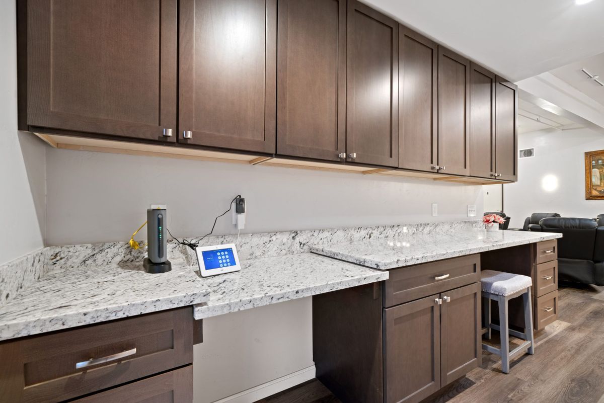 A modern kitchen with dark wood cabinets and a granite countertop, featuring various small appliances.