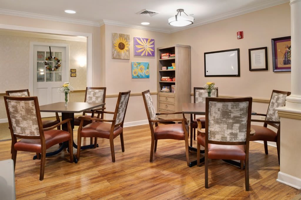 A cozy dining area with wooden flooring, decorated walls, and neatly arranged tables and chairs.
