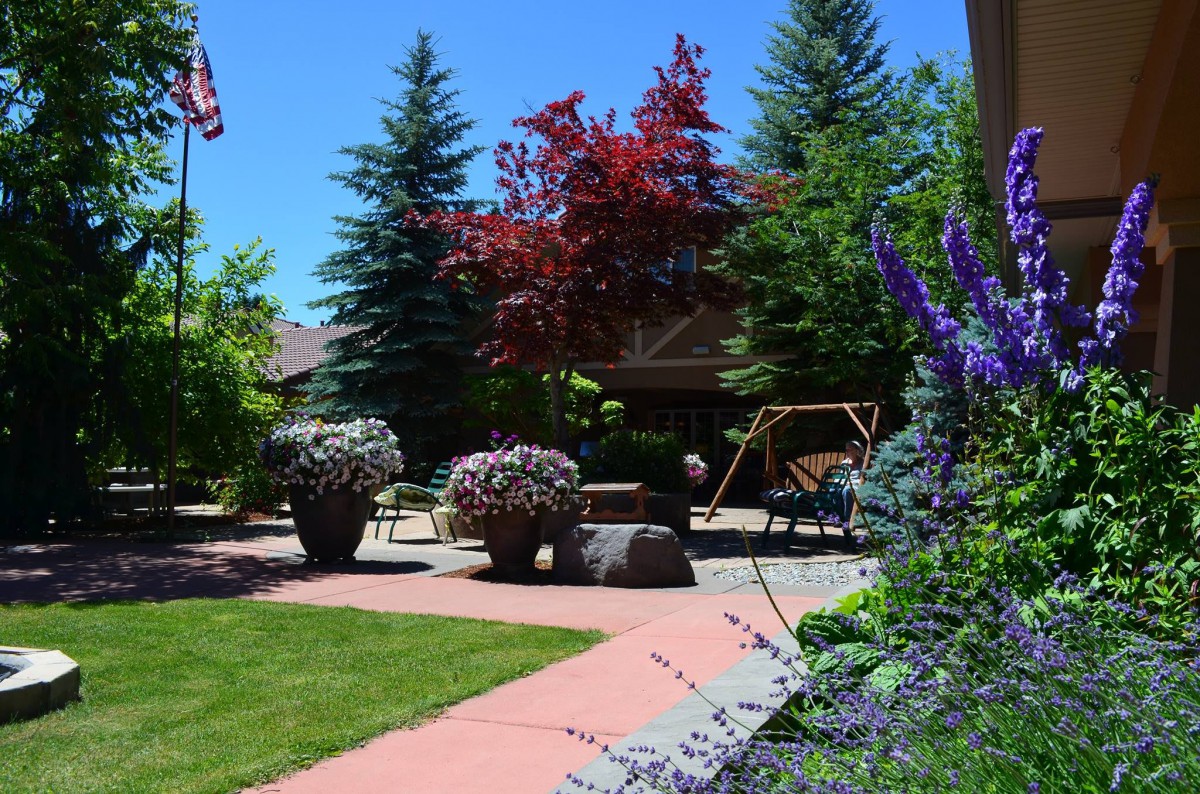 A beautifully landscaped garden with lush greenery, colorful flowers, and a peaceful patio area.