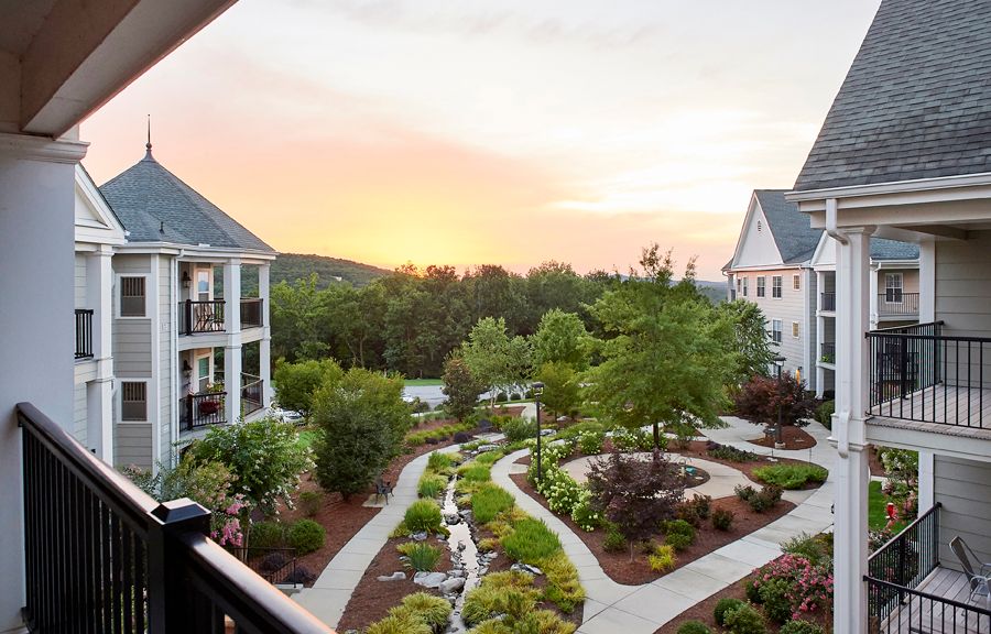 A beautiful residential garden with pathways, surrounded by buildings at sunset.