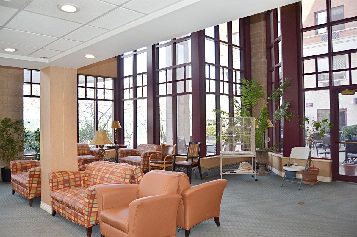 A spacious lounge area featuring comfortable seating, large windows, and indoor plants.