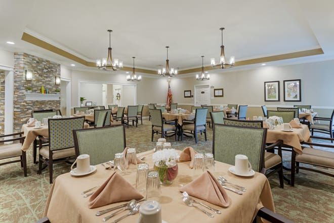 An elegant dining room with neatly arranged tables and chandeliers.