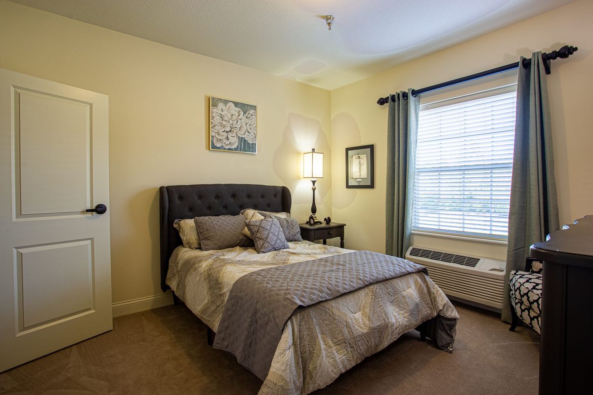 A cozy and well-decorated bedroom with a bed, lamp, and window curtains.