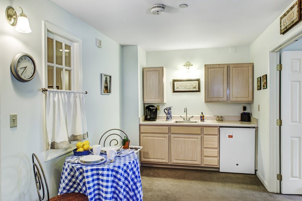 Cozy kitchen with a checkered tablecloth and wooden cabinets.