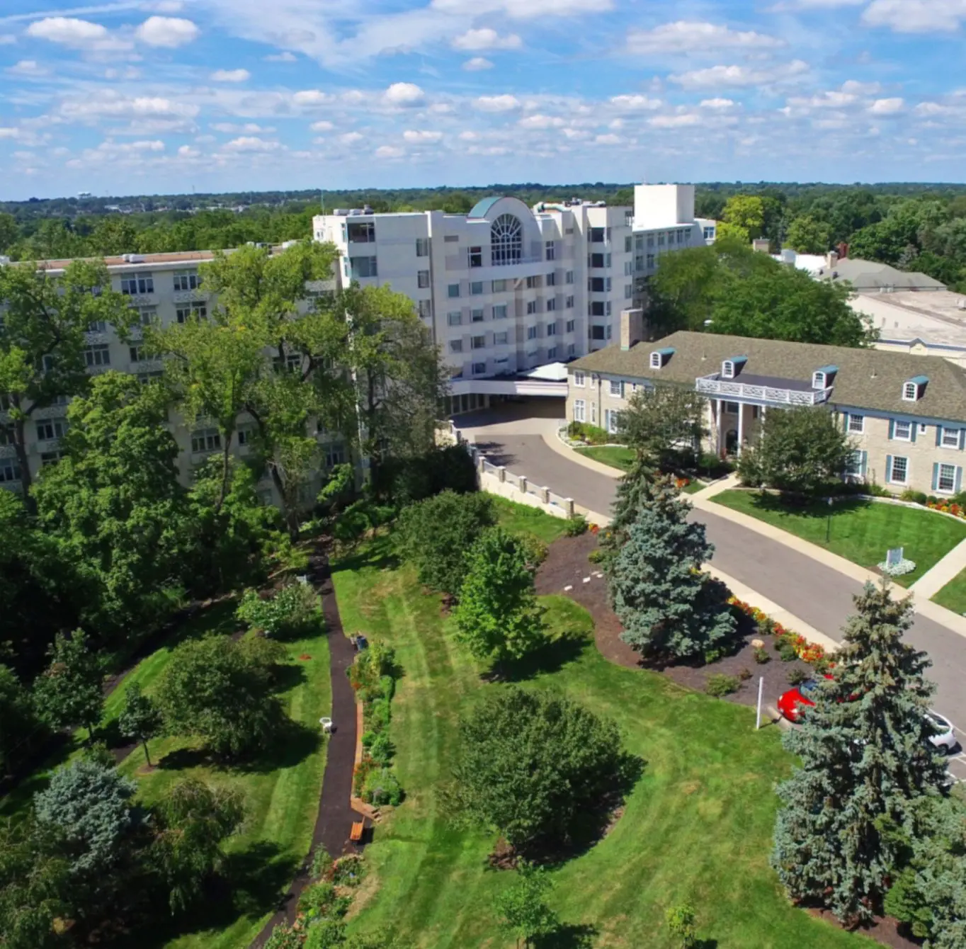 Aerial view of a building surrounded by lush greenery and trees under a partly cloudy sky.