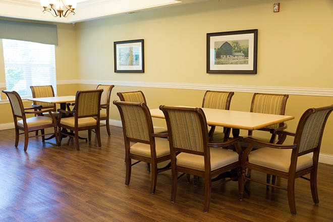 A dining room with wooden chairs and tables, featuring framed artwork on the walls.