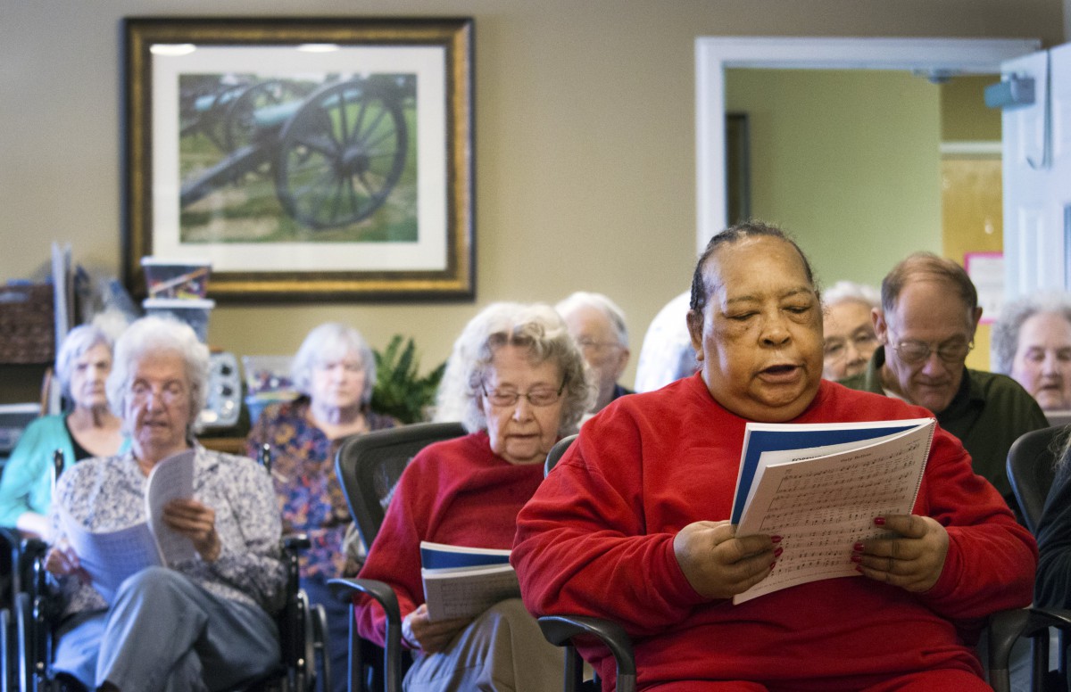 A group of elderly individuals participating in a reading session at a community center.