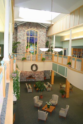 A spacious and welcoming lobby with a combination of stone elements and natural light, featuring comfortable seating and greenery.