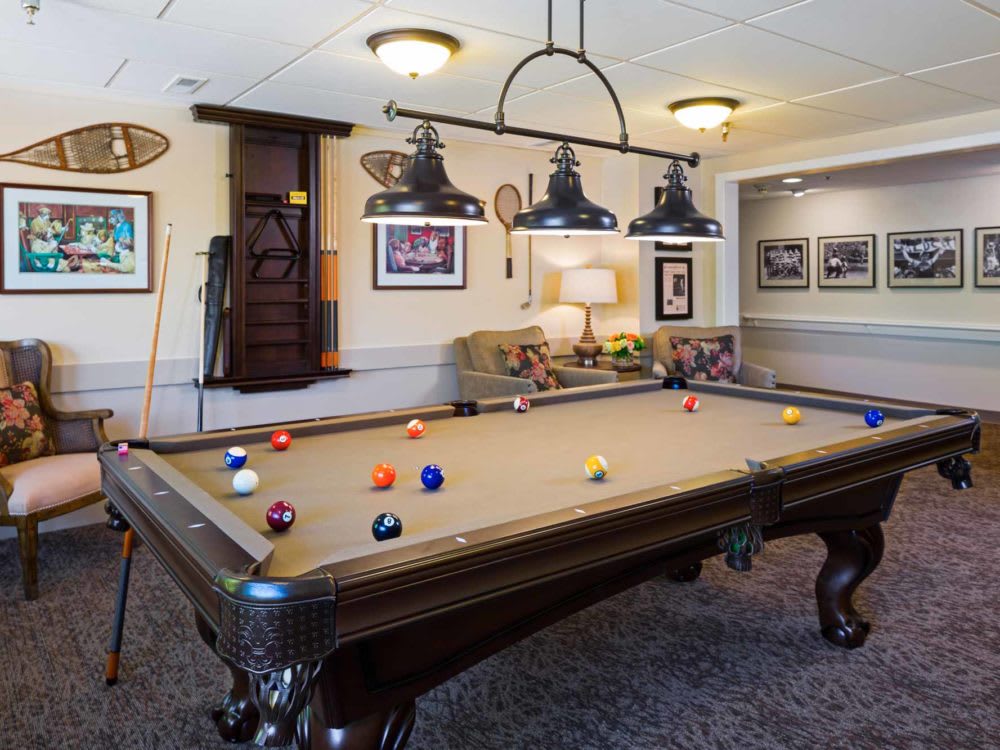 A cozy game room featuring a classic billiard table, stylish lighting, and framed artwork.