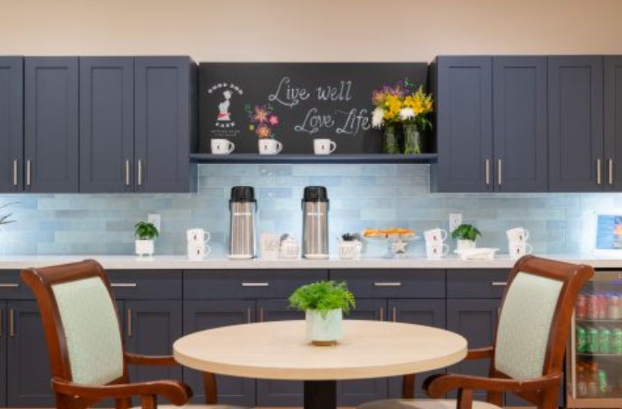 A modern kitchen setup featuring a coffee station with a decorative chalkboard and potted plants.