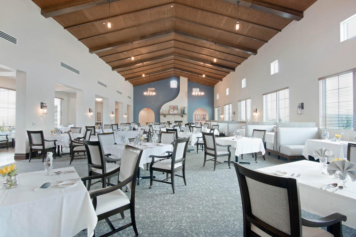 An elegant restaurant interior with white tablecloths and a wooden ceiling.
