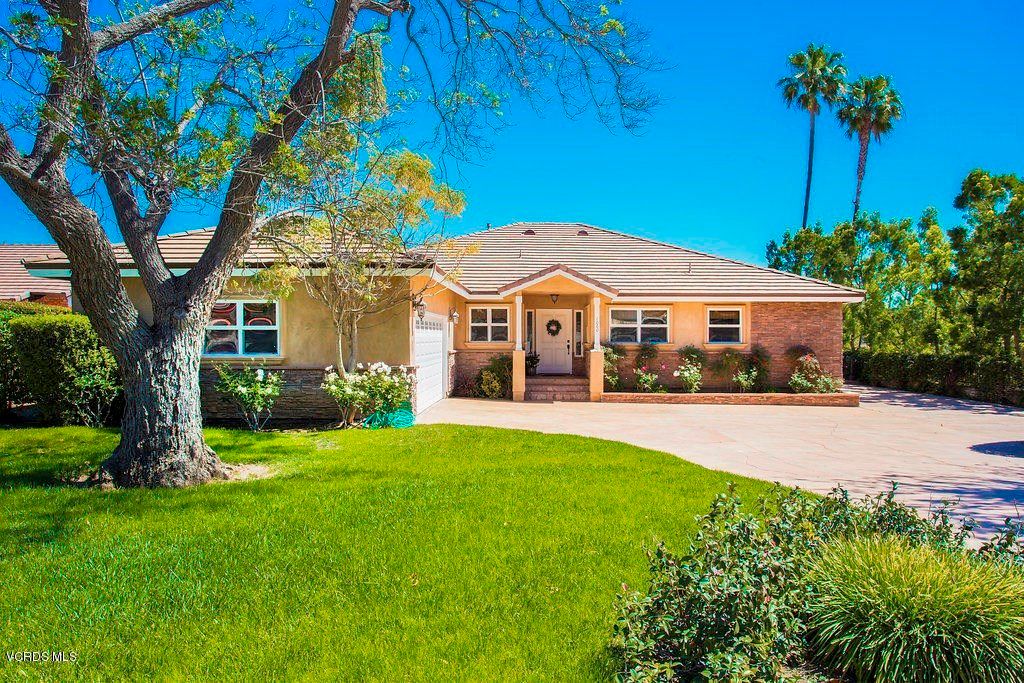 A suburban house with a well-maintained lawn and clear blue sky.