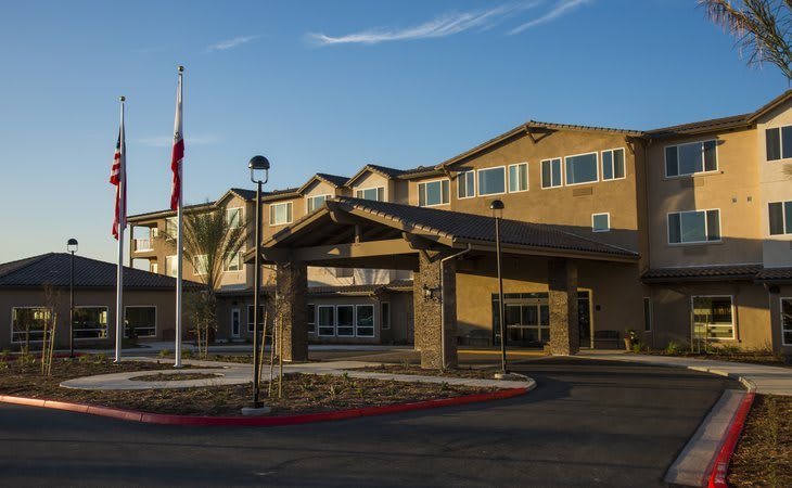 A residential building with a prominent entrance, featuring a flagpole under a clear sky.