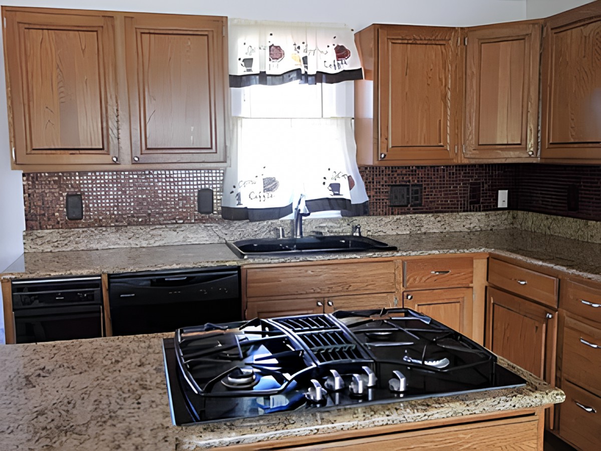 A modern kitchen with a stove, wooden cabinets, and a window above the sink.