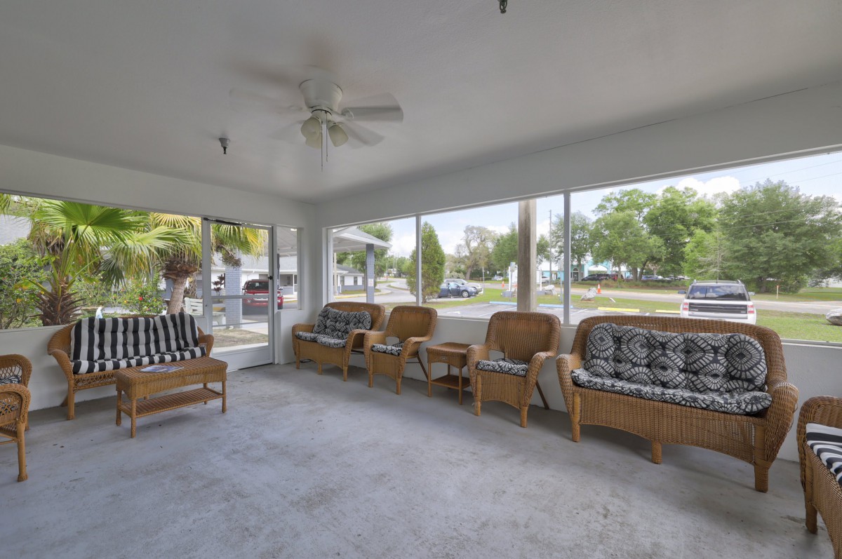 A cozy sunroom featuring rattan furniture and large windows letting in natural light.