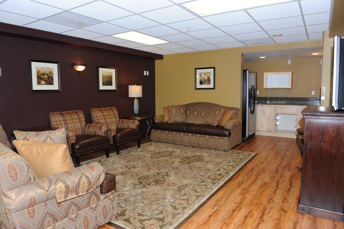 A cozy living room featuring a sofa, armchairs, a carpet on a hardwood floor, and wall art.