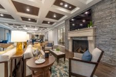 A stylish living room featuring modern decor with a coffered ceiling, comfortable seating, and a cozy fireplace.