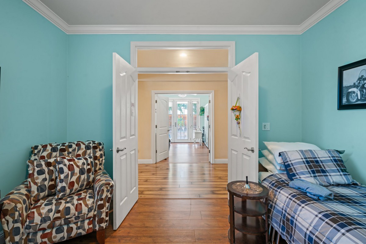 A cozy living space with open double doors, featuring colorful walls and hardwood flooring.