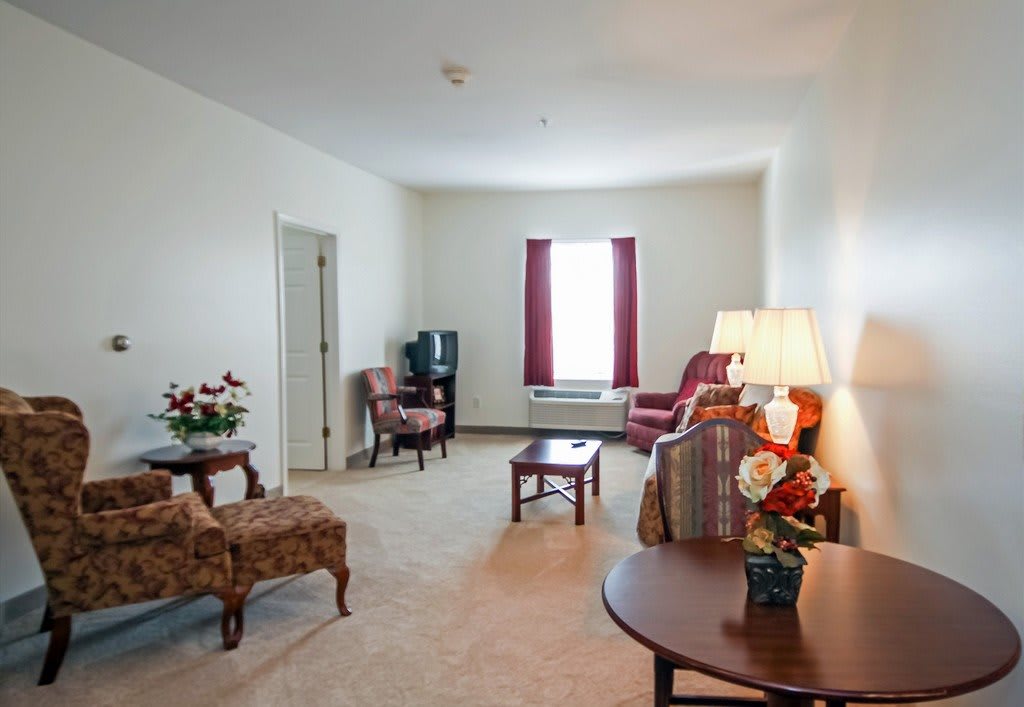 A traditional living room with armchairs, a TV, and a lamp.
