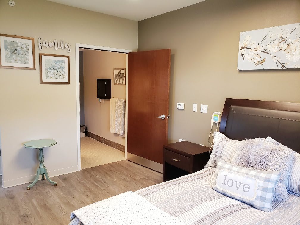 A cozy bedroom with a bed, nightstand, and decorative wall art.