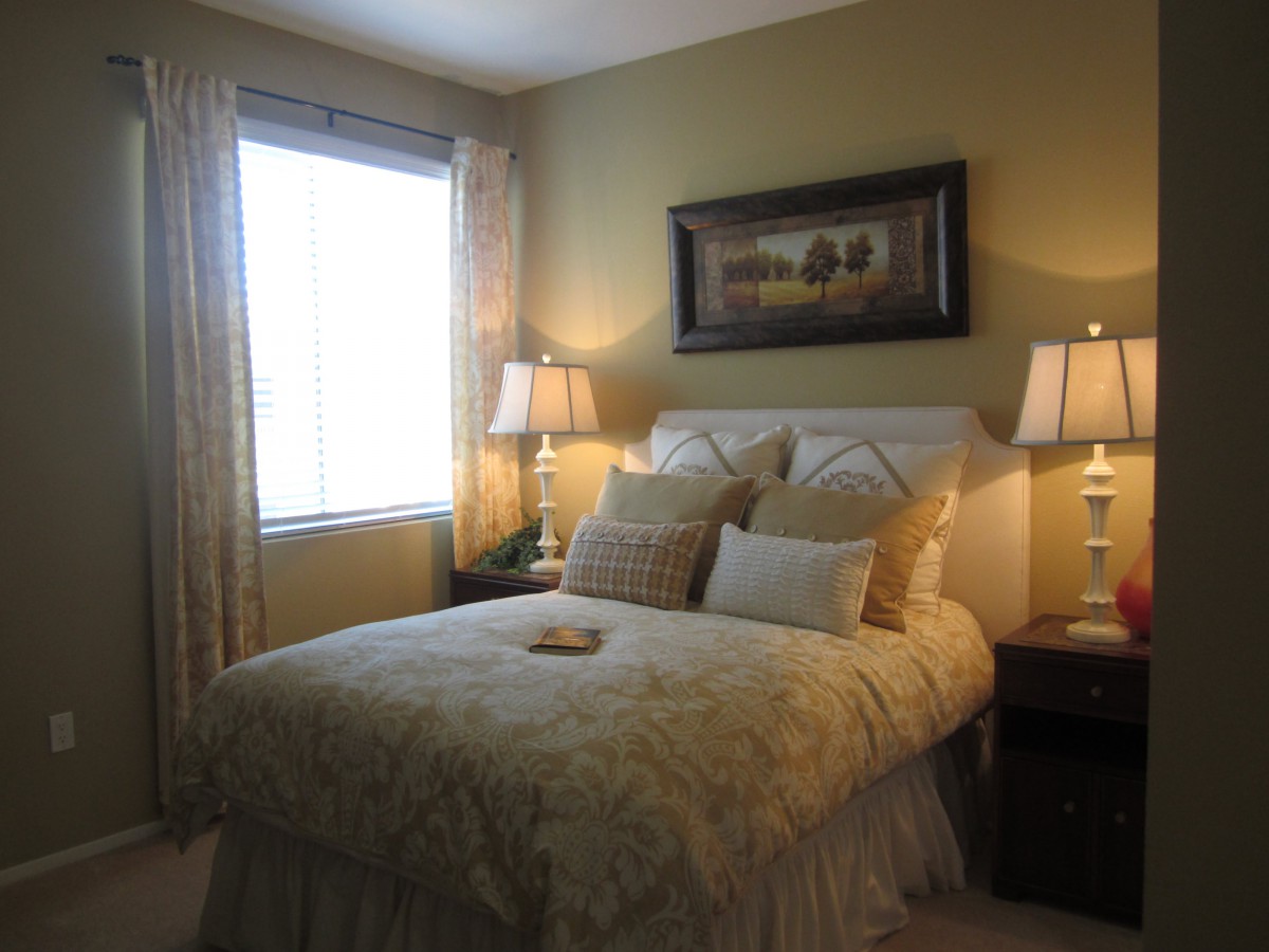 A cozy bedroom with a well-decorated bed, lamps on bedside tables, and a painting above the headboard.