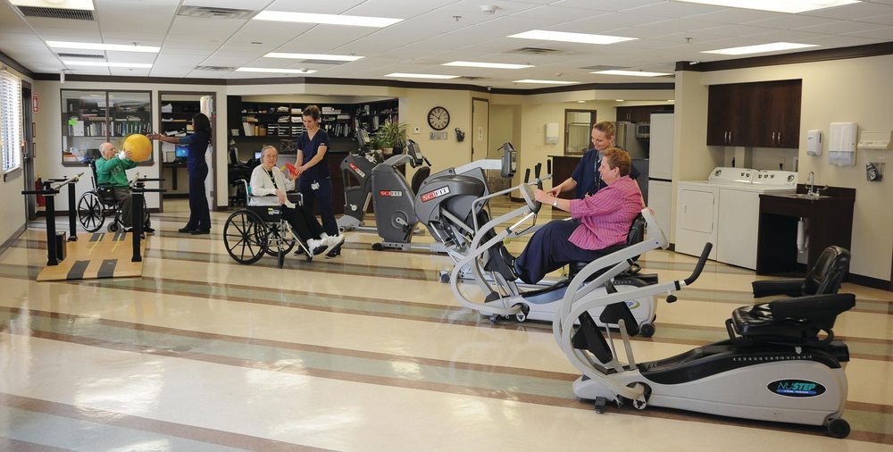 Patients and healthcare staff engage in physical rehabilitation exercises using specialized equipment in a healthcare facility.