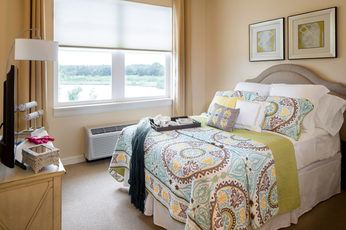 A cozy and well-decorated bedroom with a large window letting in natural light.