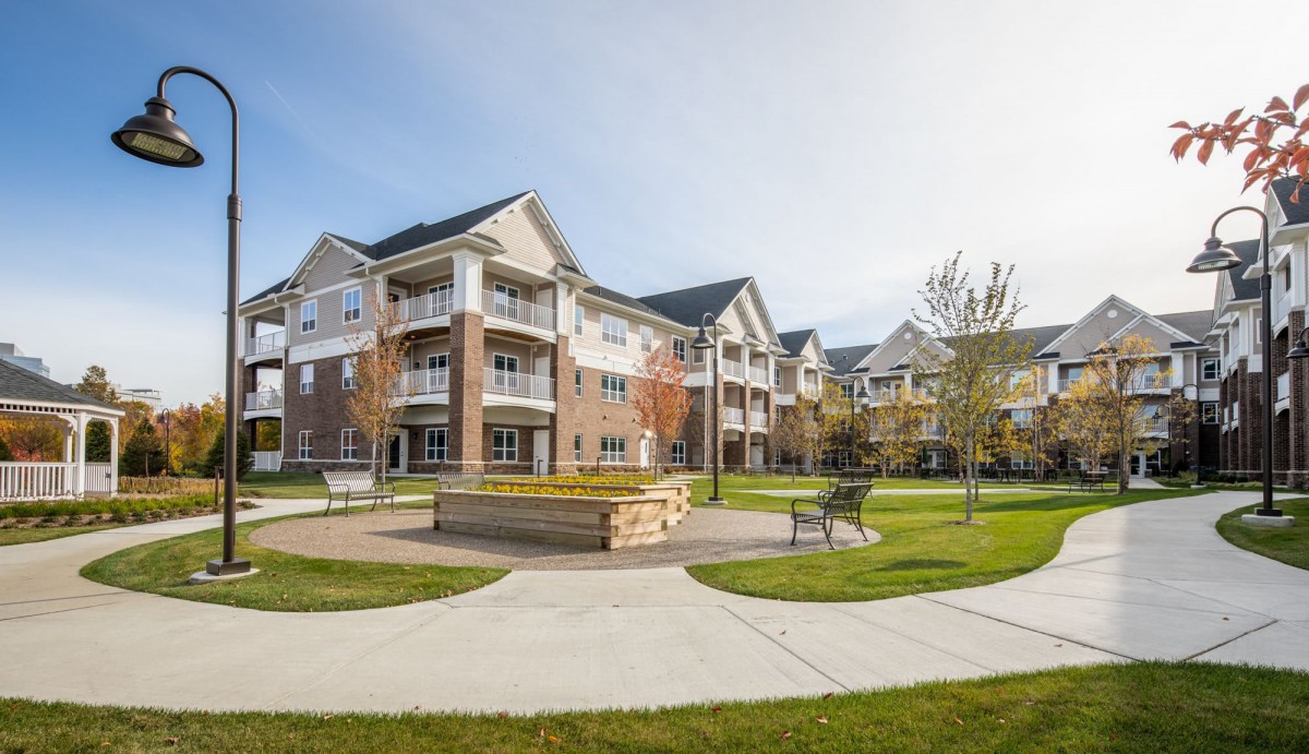 A modern apartment complex featuring landscaped courtyards and outdoor seating areas.