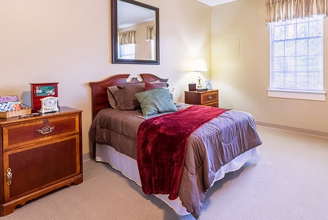 A cozy bedroom with a neatly made bed, nightstands, and a wall mirror.