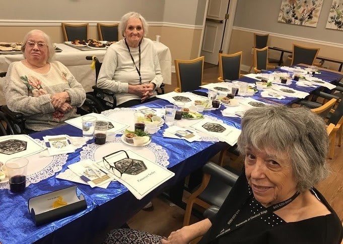 A group of elderly individuals enjoying a social gathering around a table indoors.