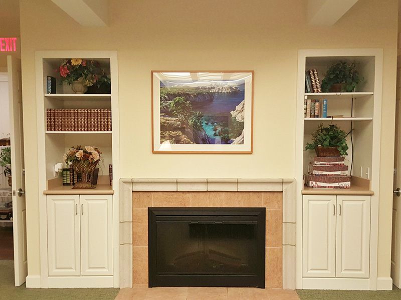 A cozy living room with a central fireplace, surrounded by built-in shelves filled with books and decorative items, and a piece of artwork above the mantel.