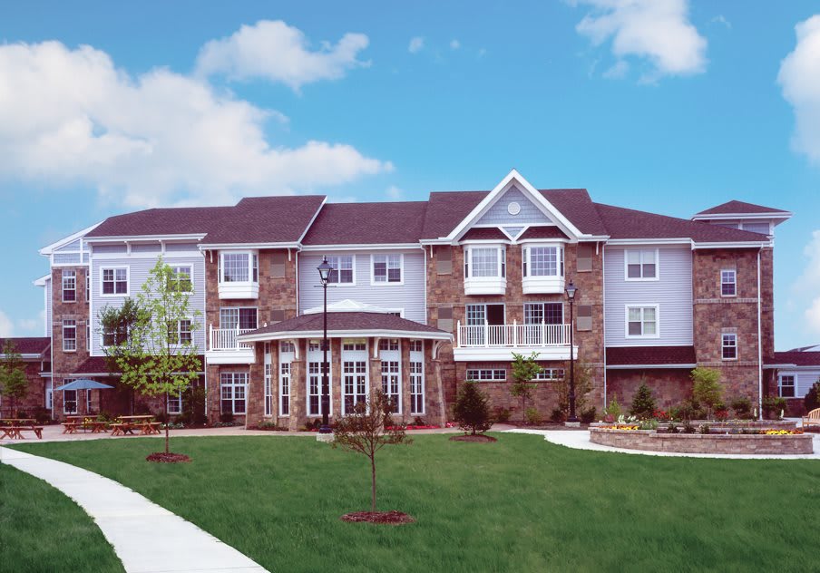 A modern residential building with a well-maintained lawn and clear blue sky.