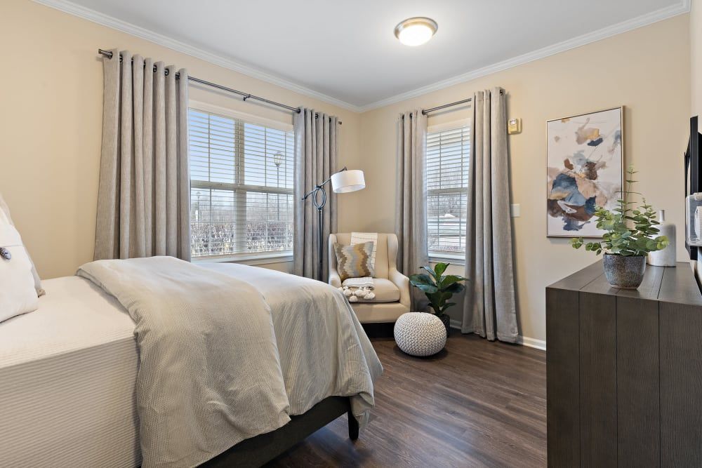 A bright and cozy bedroom with modern decor, featuring a large bed, armchair, and elegant curtains.