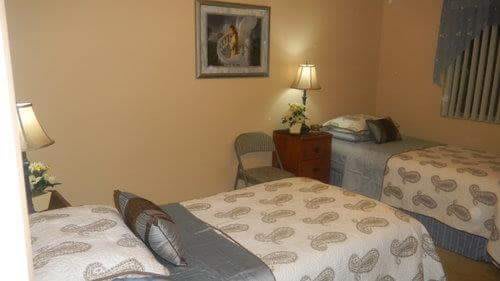 A cozy bedroom with two single beds, a nightstand with a lamp, and framed artwork on the wall.