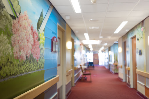 A vibrant hallway in a hospital featuring colorful murals and comfortable seating.