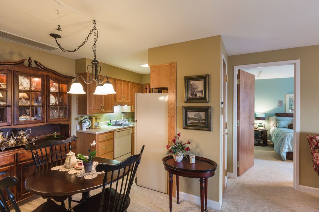 A cozy kitchen and dining area with wooden cabinets, a table set for dining, and warm lighting.