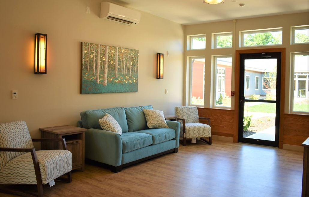 A modern living room with a blue sofa, elegant artwork, and ample natural light.