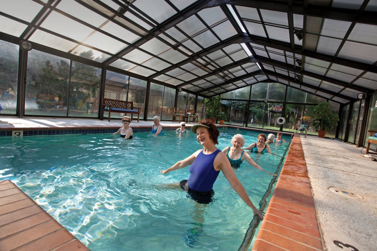 A group of people participating in a water aerobics class in an indoor pool.