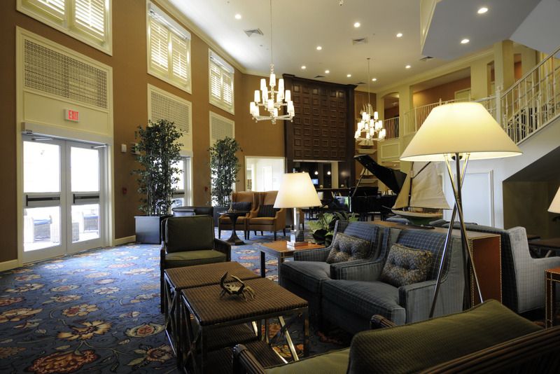 A well-decorated hotel lobby featuring comfortable seating, elegant chandeliers, and indoor plants.