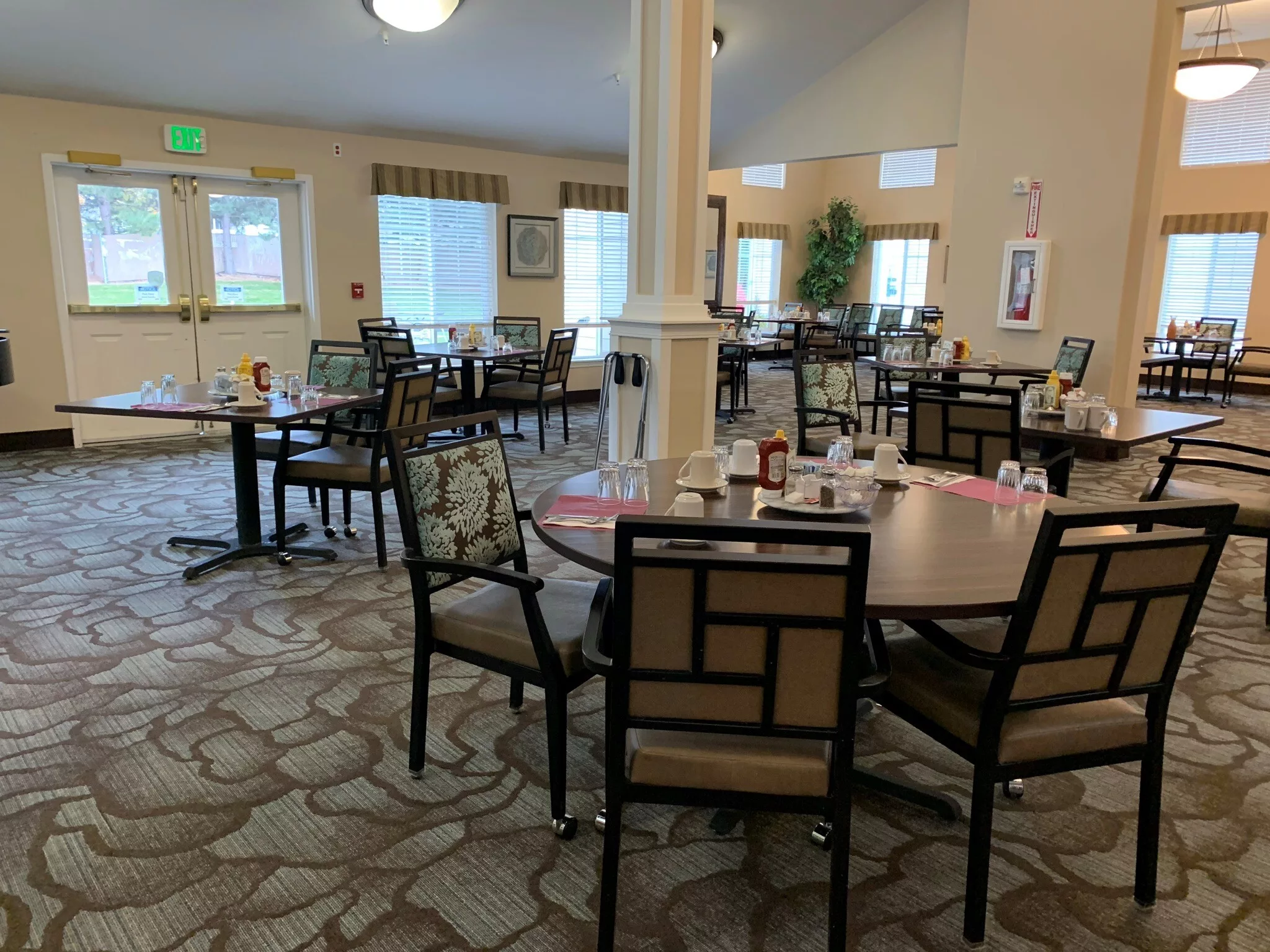 An empty dining room with neatly arranged tables and chairs, featuring soft lighting and tasteful decor.