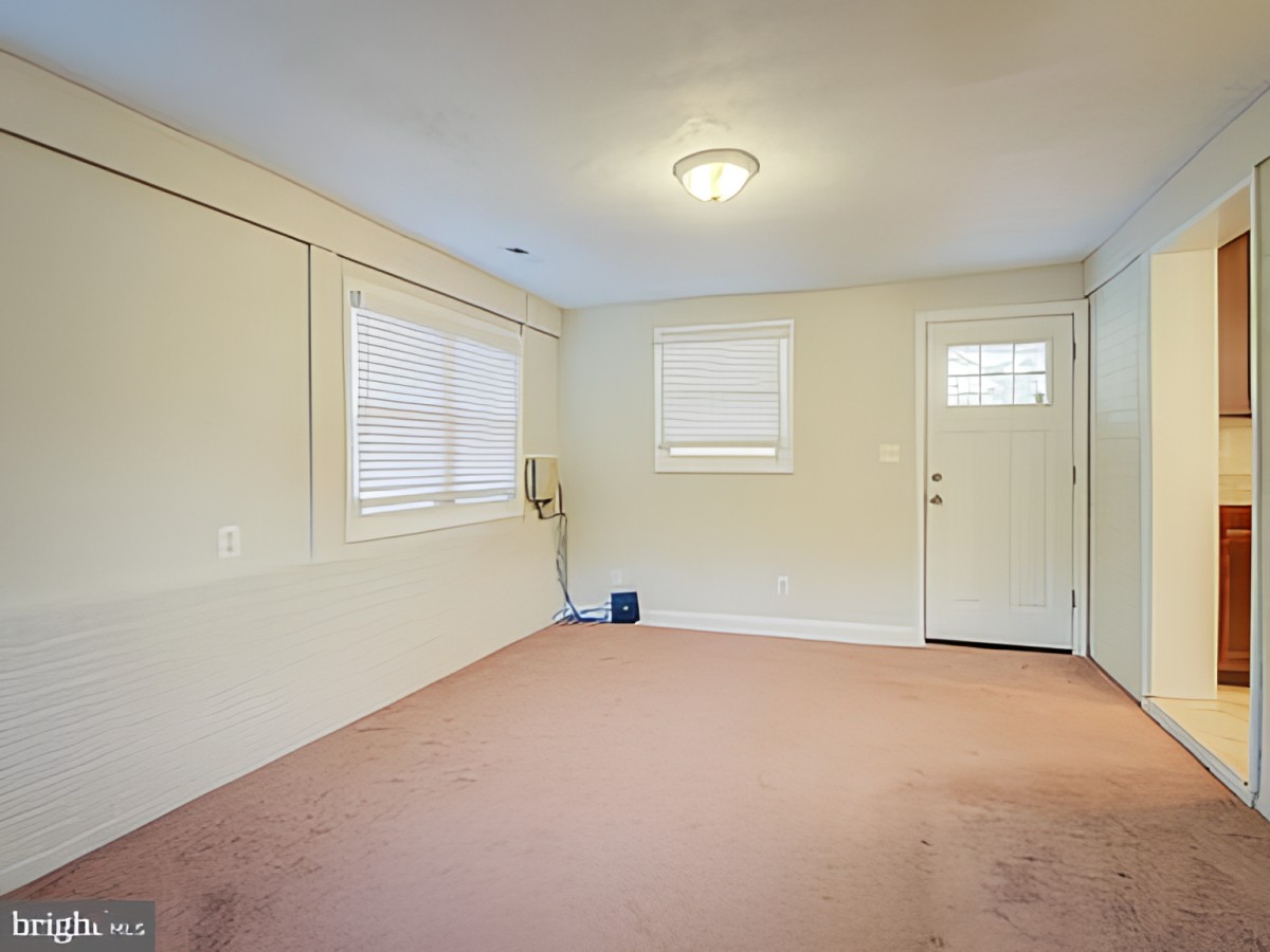 A simple room interior with carpet, windows, and a door.
