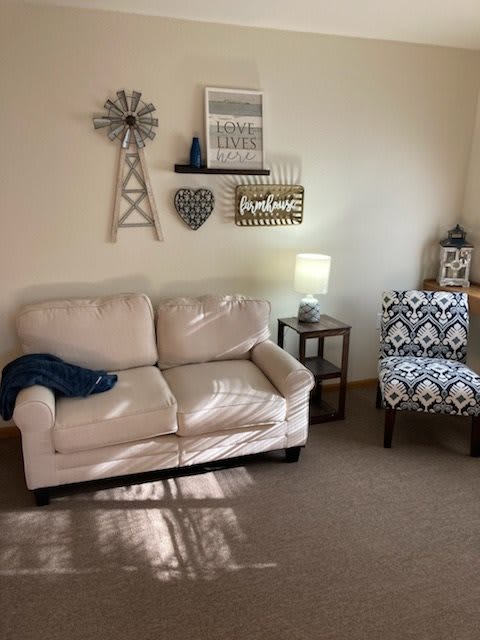 A cozy living room with a cream sofa, patterned armchair, and decorative wall art.