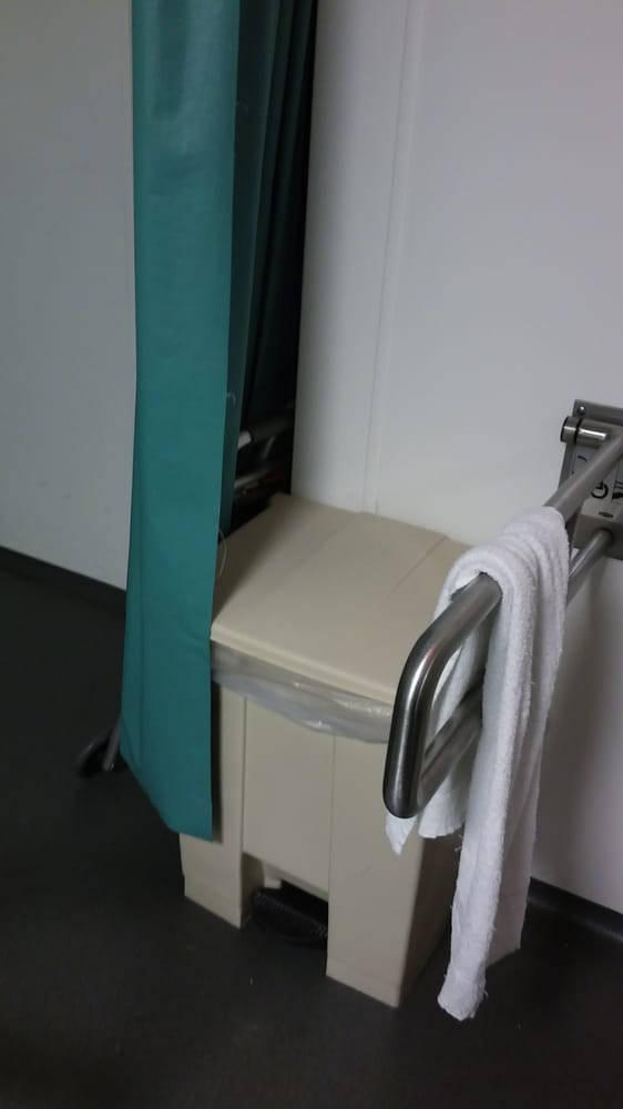 A bathroom interior with a towel hanging on a grab bar next to a privacy curtain.