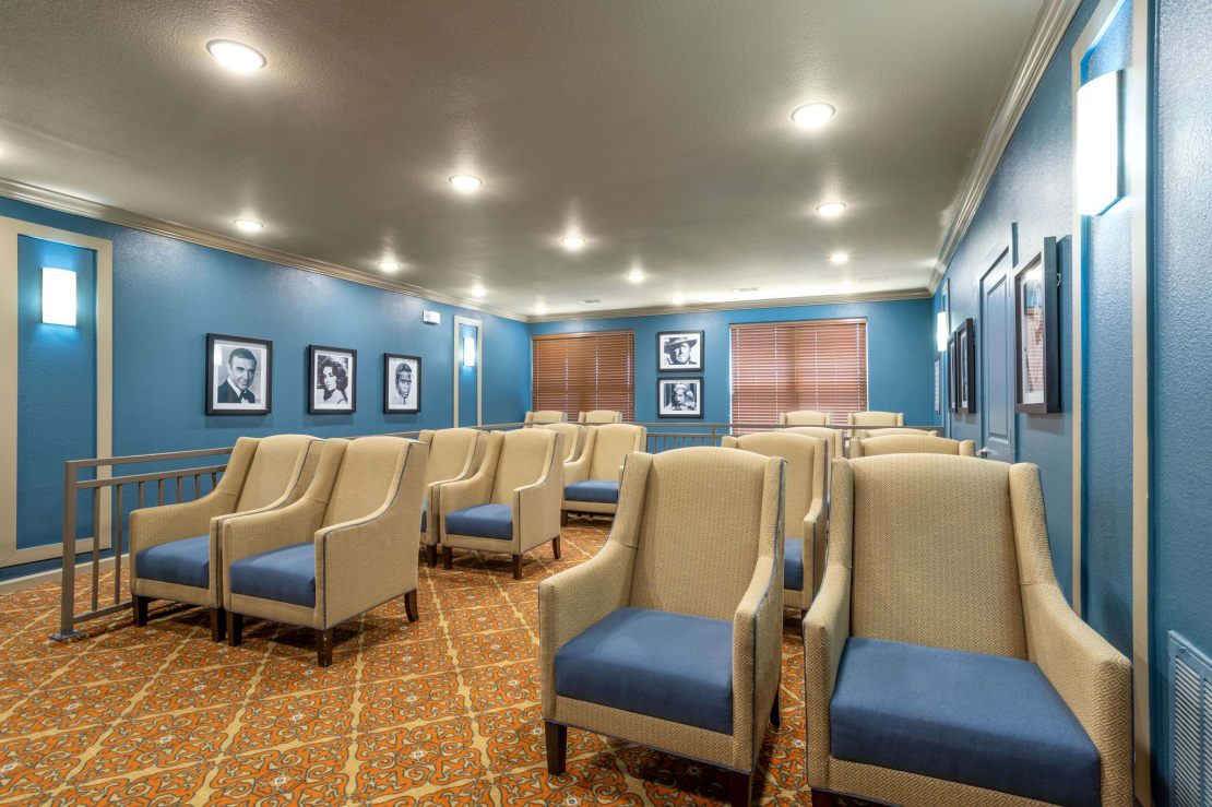 A neatly arranged small theater or conference room with comfortable seating and blue walls.